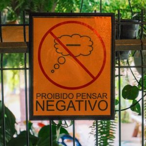 Cartel naranja con el texto Prohibido Pensar Negativo para mantener una actitud positiva ante los problemas.